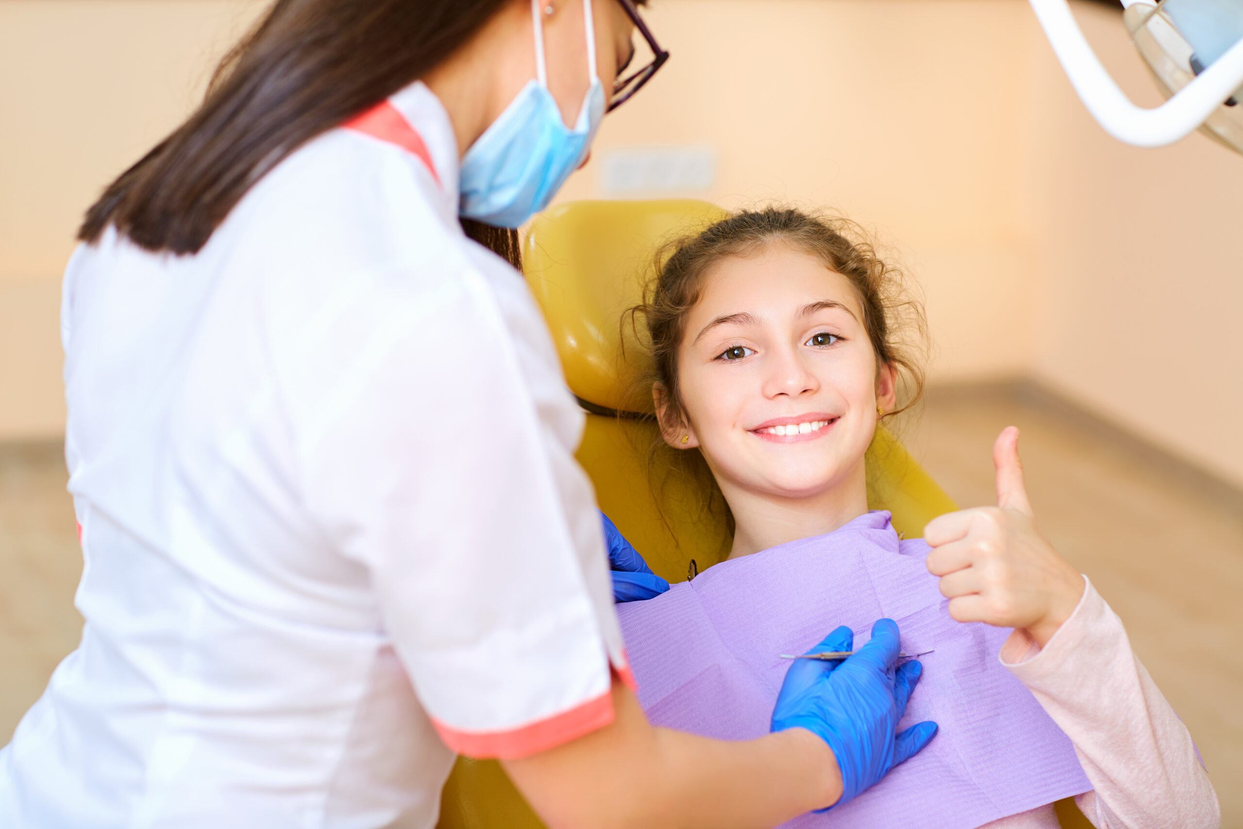 Woman dentist treats your child's teeth in the dental office.