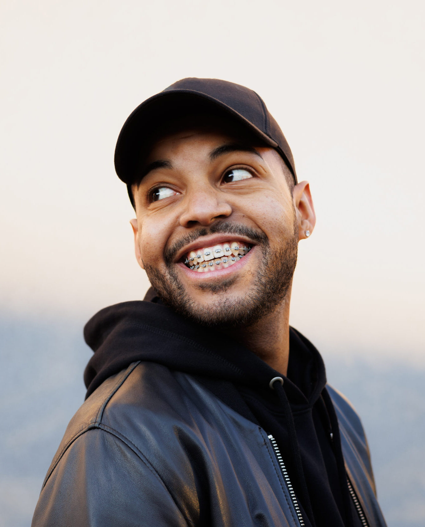 Portrait of cheerful african american man in baseball cap standing near wall with shadow